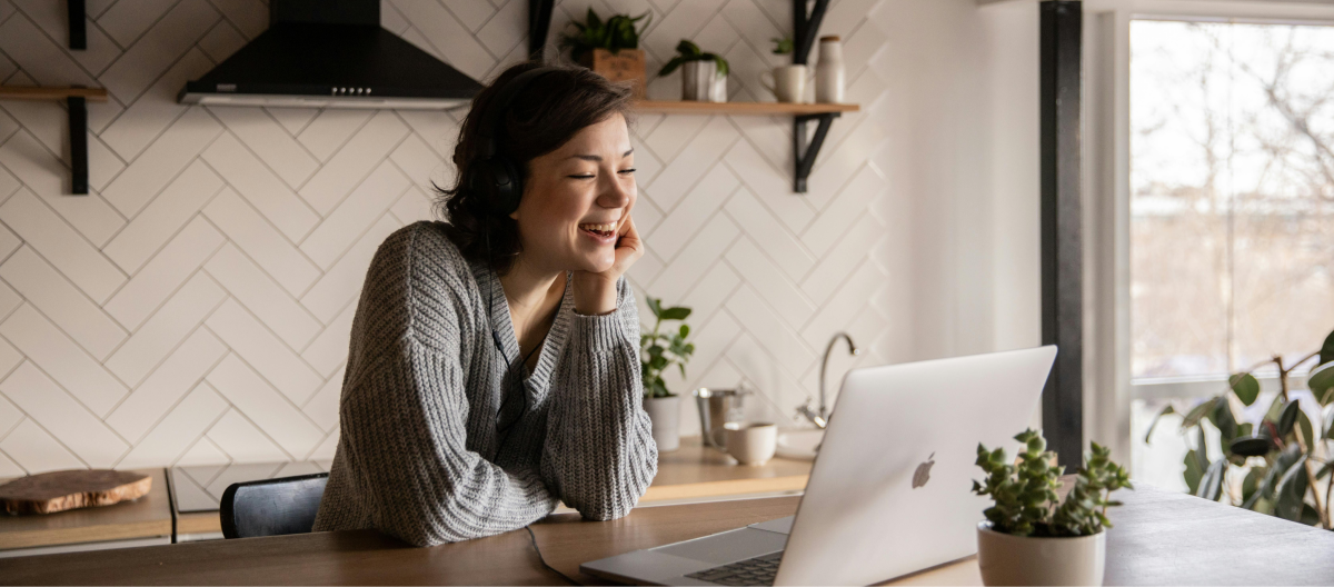 Woman smiling at a laptop in her kitchen